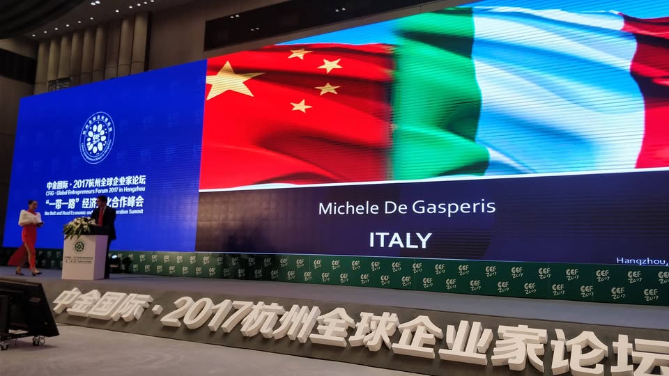 Michele De Gasperis sul palco del China Global Entrepreneurs Forum con le bandiere italiana e cinese
